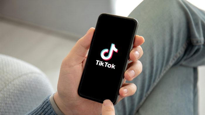 Man holding iPhone X with streaming service media video TikTok